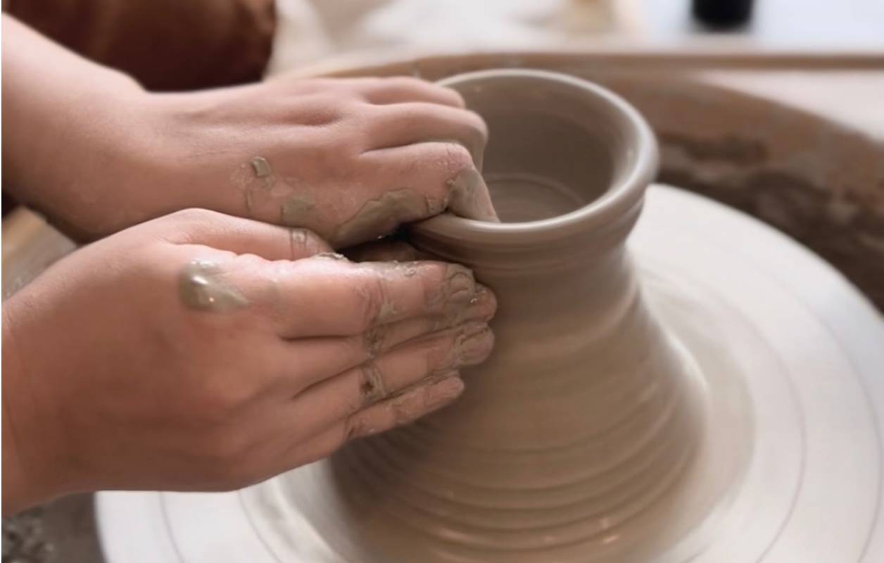 Close-up of hands shaping clay on a pottery wheel